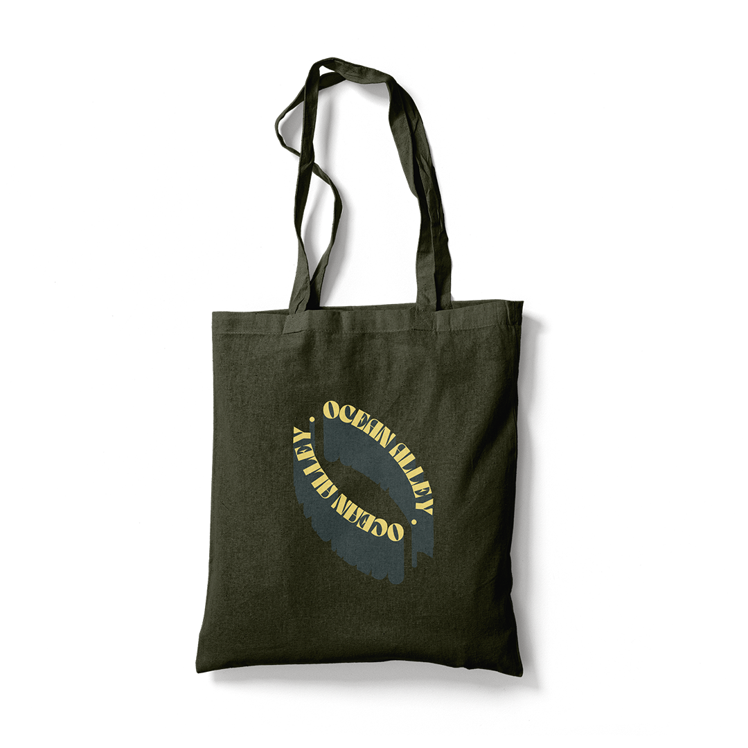 Dark green canvas tote bag with yellow text from Ocean Alley Black Tote collection